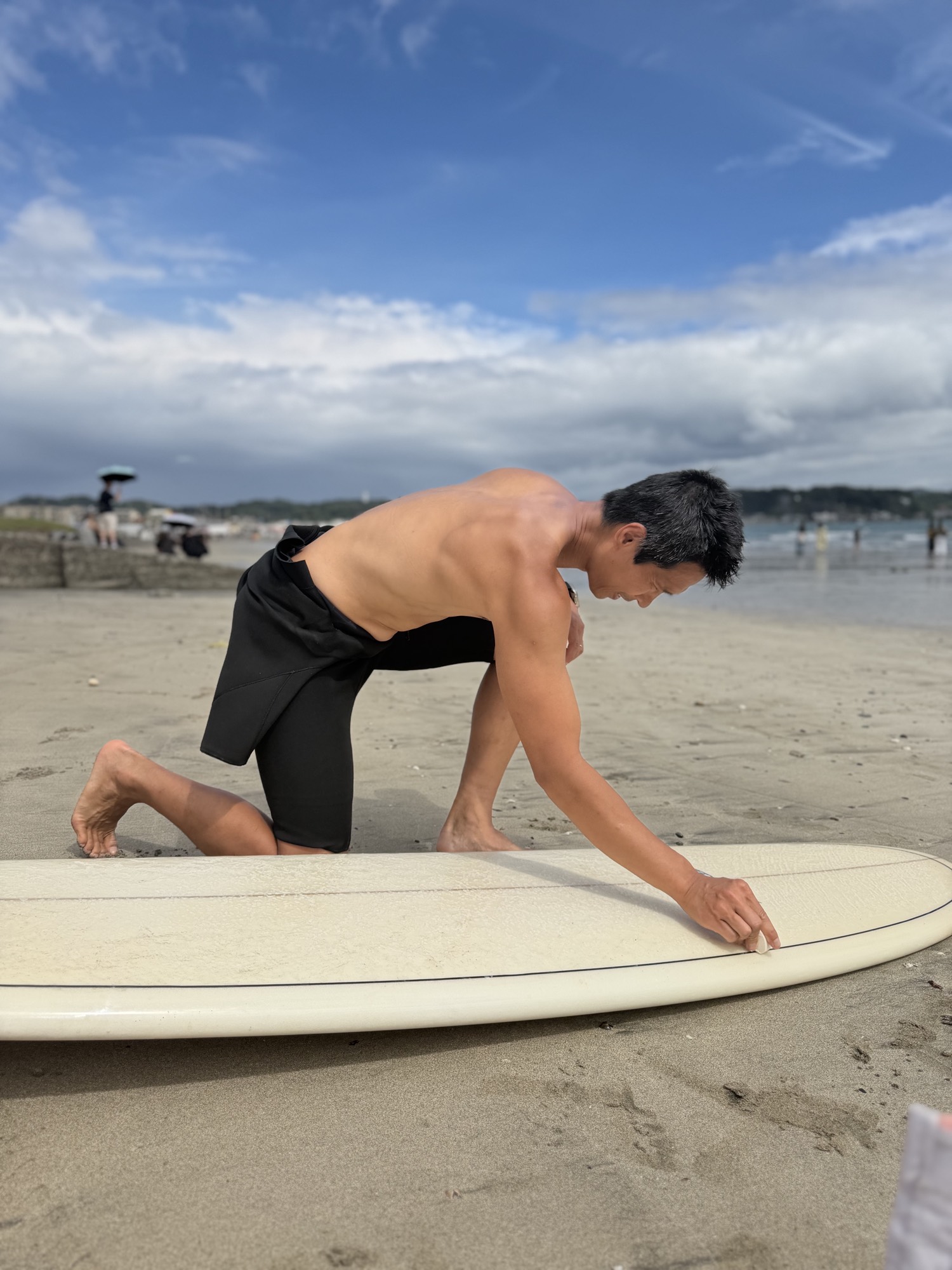 Waxing a surfboard on the sand